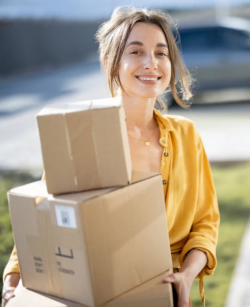 Woman holding parcels on the street in front of the house