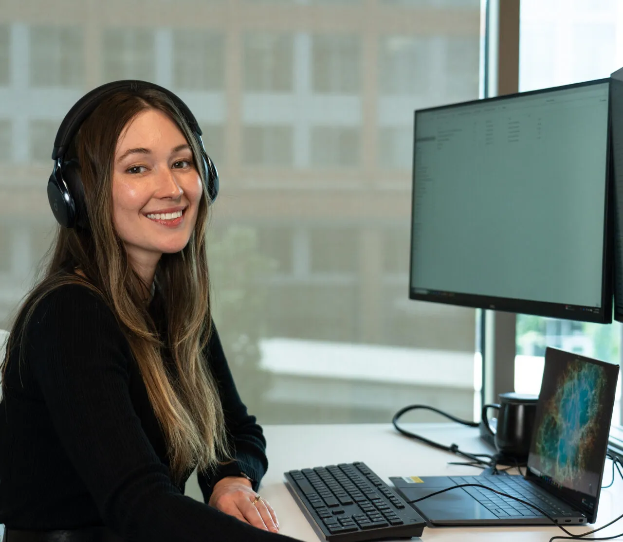 Asure Page Image Woman sitting at her workstation with headset on smiling